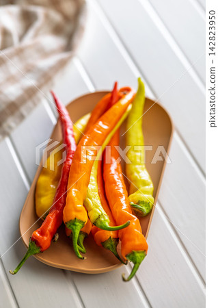 Close-Up Fresh Orange, Yellow and Red Chili Peppers on a Platter Ready for Cooking 142823950
