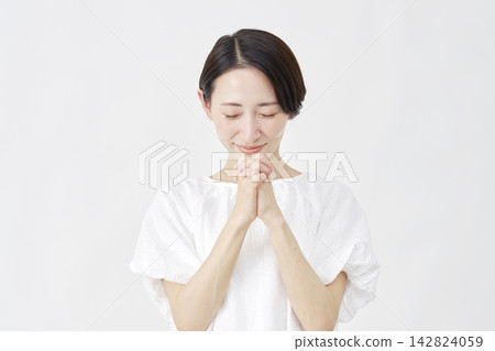 A middle-aged woman praying against a white background. A middle-aged woman praying against a white background. 142824059