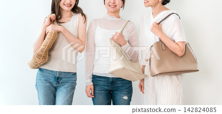 Fashion image of three stylish young women lined up with their bags. Fashion image of three stylish young women lined up with their bags. 142824085