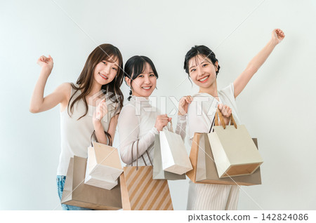 Three young women, smiling and enjoying shopping with shopping bags in hand. Three young women, smiling and enjoying shopping with shopping bags in hand. 142824086