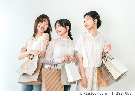 笑容滿面的女人們手提購物袋,享受著購物的樂趣。 笑容滿面的女人們手提購物袋,享受著購物的樂趣。 142824092