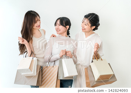 笑容滿面的女人們手提購物袋,享受著購物的樂趣。 笑容滿面的女人們手提購物袋,享受著購物的樂趣。 142824093
