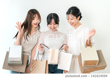 女人們面帶笑容,興奮地看著自己的購物袋。 女人們面帶笑容,興奮地看著自己的購物袋。 142824094