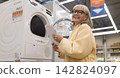 Senior woman shopping for new laundry appliances at a retail store 142824097