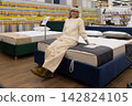 Senior woman shopping for new bed and mattress in furniture store 142824105