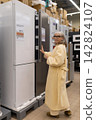 Senior woman considering refrigerators in a large retail appliance store 142824107