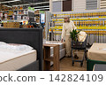 Senior woman pushing shopping cart while browsing mattresses in a retail store 142824109