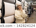 Senior woman considering choices for home decor in a wallpaper store 142824124