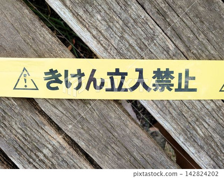 Warning tape that reads "Danger: No Entry" is placed on the wooden deck. Warning tape that reads "Danger: No Entry" is placed on the wooden deck. 142824202