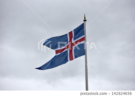 National flag of Iceland against a cloudy sky National flag of Iceland against a cloudy sky 142824656