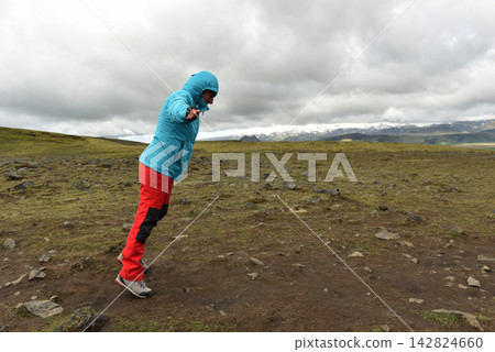 Hiker battling strong wind on a mountain plateau in Landmannalaugar Iceland 142824660