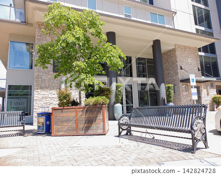 Black metal park bench on a stone walkway next to a wooden planter box at the Baker Condominiums entrance - June 13, 2026 Ruston WA, USA Black metal park bench on a stone walkway next to a wooden planter box at the Baker Condominiums entrance - June 13, 2026 Ruston WA, USA 142824728