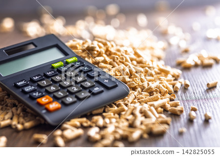 Calculator on Wood Pellets Representing Energy Costs, Biomass Heating, Renewable Fuel Budgeting and Finance 142825055