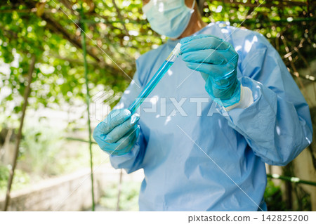 Agricultural scientist holding a test tube with blue chemical solution for plant biotechnology research Agricultural scientist holding a test tube with blue chemical solution for plant biotechnology research 142825200
