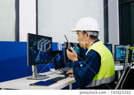 Industrial engineer in a safety helmet and reflective vest monitors digital dashboards and control systems, combining technology, data analysis, workplace safety Industrial engineer in a safety helmet and reflective vest monitors digital dashboards and control systems, combining technology, data analysis, workplace safety 142825282