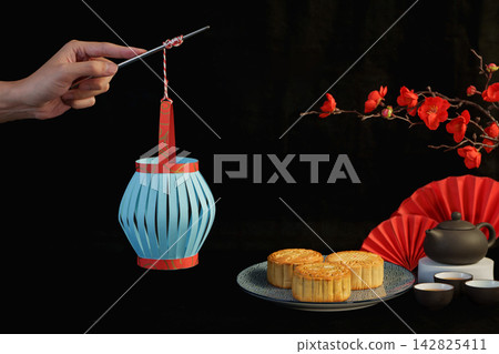 Cropped hand holding paper lantern with mooncakes for Mid-Autumn Festival Cropped hand holding paper lantern with mooncakes for Mid-Autumn Festival 142825411