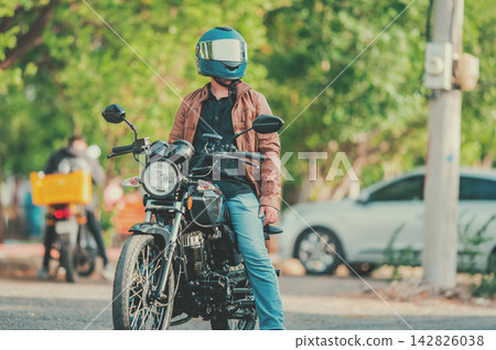 Portrait of a young motorcyclist on the road, looking to the side Portrait of a young motorcyclist on the road, looking to the side 142826038