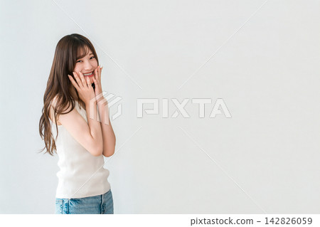 一位年輕女子麵帶微笑,手輕撫臉頰。這是一張展現美麗肌膚和護膚理念的精美圖片。 一位年輕女子麵帶微笑,手輕撫臉頰。這是一張展現美麗肌膚和護膚理念的精美圖片。 142826059