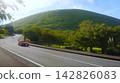 A red sports car (Mazda) drives along a road near Mt. Omuro (Izu Kogen) in early autumn. 142826083
