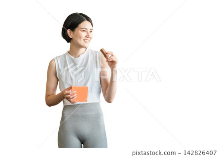 Young Asian woman in yoga wear eating a protein/nutrition bar Young Asian woman in yoga wear eating a protein/nutrition bar 142826407