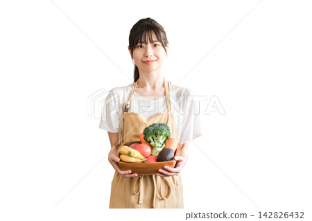 Asian woman in an apron, housewife, holding vegetables. 142826432