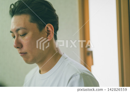 The profile of a man in his late thirties or early forties, quietly hunched over at the bathroom sink in the morning. The profile of a man in his late thirties or early forties, quietly hunched over at the bathroom sink in the morning. 142826559