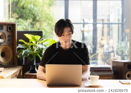 一位年輕男子正在共享辦公空間裡專心致志地使用電腦建立文件。 一位年輕男子正在共享辦公空間裡專心致志地使用電腦建立文件。 142826670
