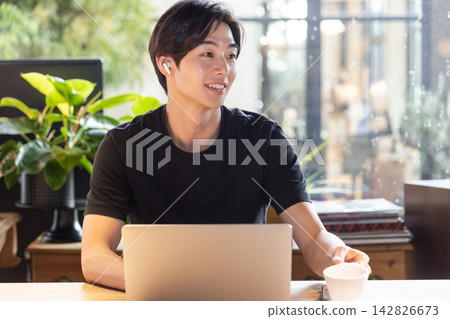 一名戴著耳機的年輕人在共享辦公空間參加線上會議。 142826673