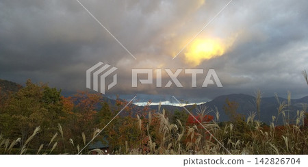 蒲葦和秋葉,夕陽透過雲層沉入秋日的山脈。 蒲葦和秋葉,夕陽透過雲層沉入秋日的山脈。 142826704