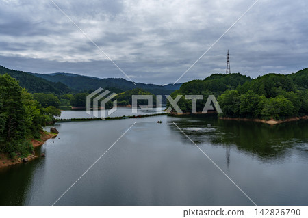A wide lake surface reflecting the sky; Nunome Dam; 35mm; blank copy space above; horizontal composition; transmission tower on the right; suitable for B0 poster. 142826790