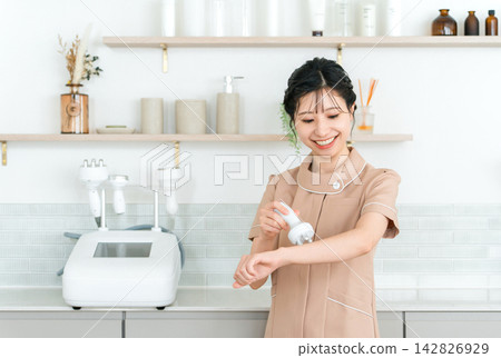 A smiling esthetician holding a beauty device. Female staff working at a beauty salon. A smiling esthetician holding a beauty device. Female staff working at a beauty salon. 142826929