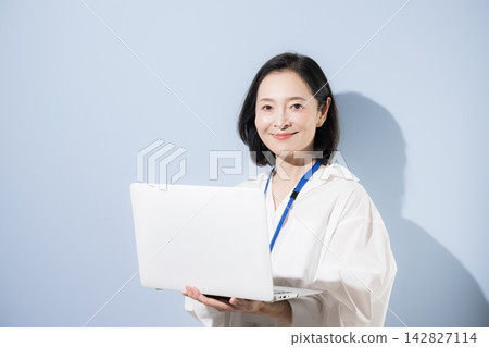 一位女上班族面帶微笑,手持筆記型電腦;她是一位在工作中運用數位科技的日本女商人。 一位女上班族面帶微笑,手持筆記型電腦;她是一位在工作中運用數位科技的日本女商人。 142827114