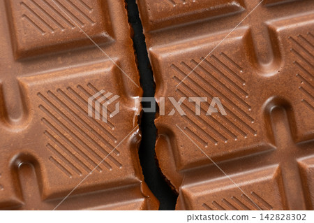Broken milk chocolate bar with geometric line pattern, texture macro background Broken milk chocolate bar with geometric line pattern, texture macro background 142828302