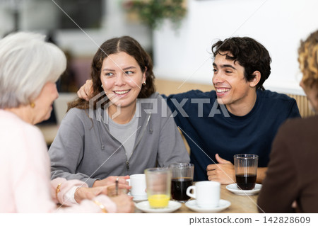 Large family is having breakfast in a cozy cafe, discussing news. Large family is having breakfast in a cozy cafe, discussing news. 142828609