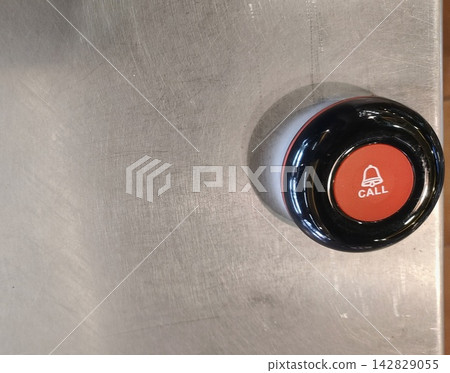 Red service call button with bell icon on a brushed stainless steel surface 142829055