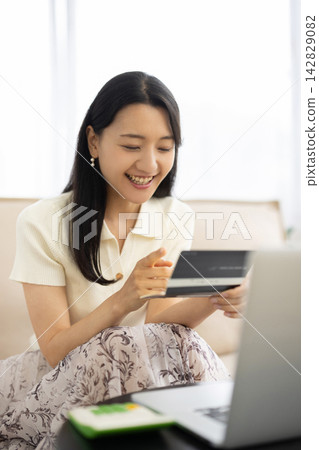 A young Japanese woman smiles while looking at her bankbook. A young Japanese woman smiles while looking at her bankbook. 142829082