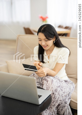 A young Japanese woman smiles while looking at her bankbook. A young Japanese woman smiles while looking at her bankbook. 142829085
