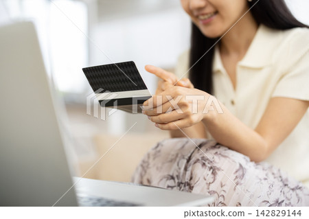 A close-up of a young woman's hands as she smiles while looking at her bankbook. 142829144