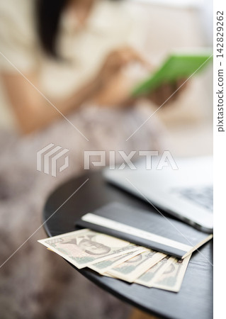 一張銀行存摺和一張10,000日元鈔票放在桌上，特寫鏡頭。 142829262