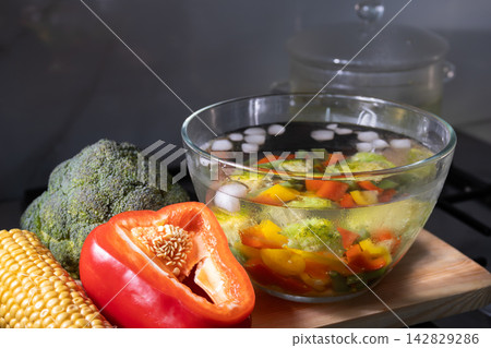 Cooling blanched vegetables in ice water on a kitchen counter with colorful produce Cooling blanched vegetables in ice water on a kitchen counter with colorful produce 142829286