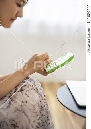 Close-up of a woman's hands using a calculator Close-up of a woman's hands using a calculator 142829315