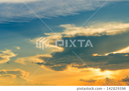 Dramatic golden sunset sky with dark clouds illuminated by sunlight, blue and orange evening atmosphere. Colorful natural cloudscape for weather, nature and scenic background concepts. Dramatic golden sunset sky with dark clouds illuminated by sunlight, blue and orange evening atmosphere. Colorful natural cloudscape for weather, nature and scenic background concepts. 142829396