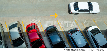 Top view of cars parked in outdoor concrete parking lot with yellow space lines and directional arrow. Crowded vehicle parking area and urban transportation infrastructure. Urban mobility concept. Top view of cars parked in outdoor concrete parking lot with yellow space lines and directional arrow. Crowded vehicle parking area and urban transportation infrastructure. Urban mobility concept. 142829397