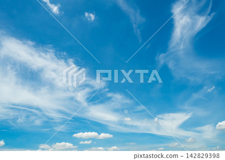 White wispy clouds across bright blue sky on a sunny day, peaceful natural cloudscape with open atmosphere for weather, climate, environment, freedom and nature background concepts. 142829398