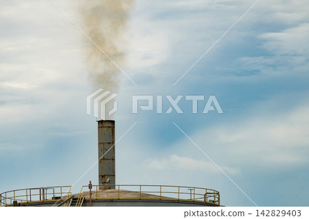 Industrial chimney releasing smoke into the atmosphere under cloudy sky. Factory air pollution, harmful emissions, environmental contamination and global warming. Climate change and poor air quality. Industrial chimney releasing smoke into the atmosphere under cloudy sky. Factory air pollution, harmful emissions, environmental contamination and global warming. Climate change and poor air quality. 142829403