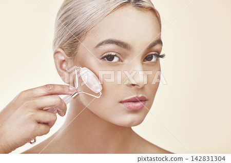 Facial roller, skincare and portrait of woman in studio with natural, health and cosmetic routine. Beauty, wellness and person with rose quartz dermatology tool for face treatment by white background Facial roller, skincare and portrait of woman in studio with natural, health and cosmetic routine. Beauty, wellness and person with rose quartz dermatology tool for face treatment by white background 142831304