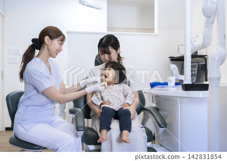 A 2-year-old child and their mother receiving toothbrushing instruction at a dental clinic. A 2-year-old child and their mother receiving toothbrushing instruction at a dental clinic. 142831854