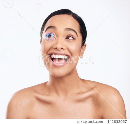 Woman, happy and bubbles for skincare in studio as facial cleaning, hygiene and glow results of treatment at spa. Smile, female person and beauty for shine of dermatology wellness on white background 142832067