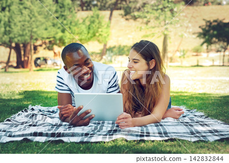 Happy couple, relax and students on tablet at park on blanket with smile for meme, funny video or streaming. Man, women or people on break with social media or online subscription for movie on lawn Happy couple, relax and students on tablet at park on blanket with smile for meme, funny video or streaming. Man, women or people on break with social media or online subscription for movie on lawn 142832844