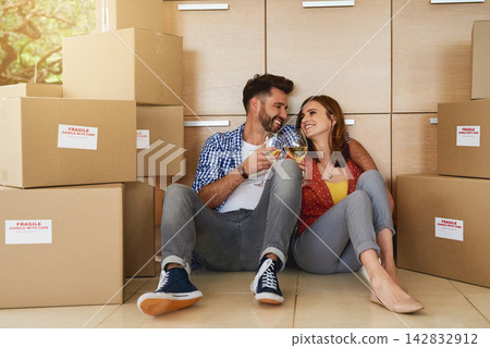Couple, boxes and wine in house for cheers, relief and celebration for moving or new home. Happy man, woman and cardboard for packaging in living space with smile, toast and happiness for mortgage Couple, boxes and wine in house for cheers, relief and celebration for moving or new home. Happy man, woman and cardboard for packaging in living space with smile, toast and happiness for mortgage 142832912